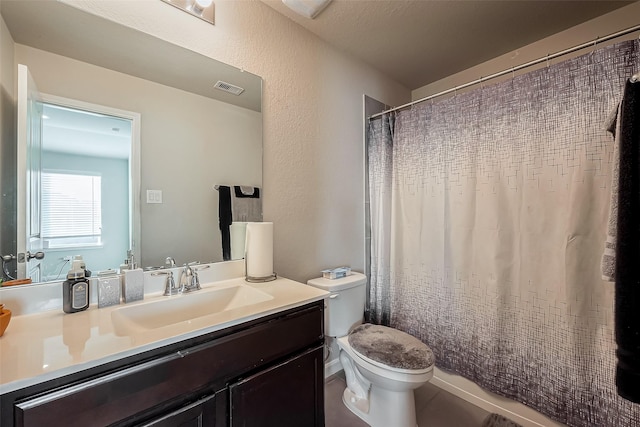 bathroom featuring toilet, a textured wall, visible vents, and vanity