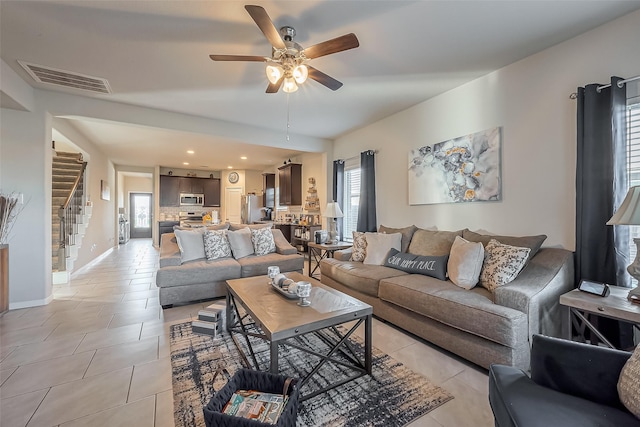 living room featuring visible vents, ceiling fan, stairway, and light tile patterned floors