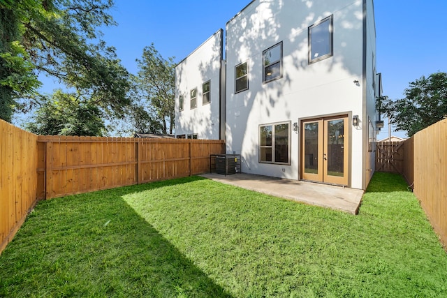 back of property with a lawn, a fenced backyard, french doors, a patio area, and stucco siding