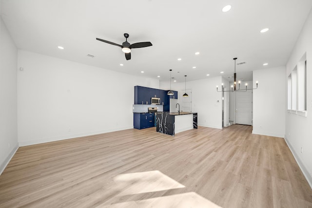 unfurnished living room featuring light wood-style flooring, recessed lighting, ceiling fan with notable chandelier, a sink, and visible vents