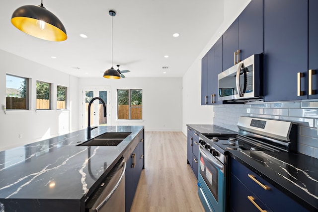 kitchen featuring blue cabinets, a sink, stainless steel appliances, light wood-type flooring, and backsplash