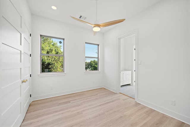 spare room featuring light wood finished floors, visible vents, and baseboards