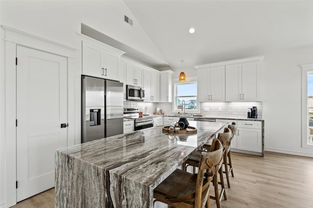 4214 Jackson Dr, Galveston, TX 77554 - kitchen featuring appliances with stainless steel finishes, visible vents, white cabinetry, and tasteful backsplash