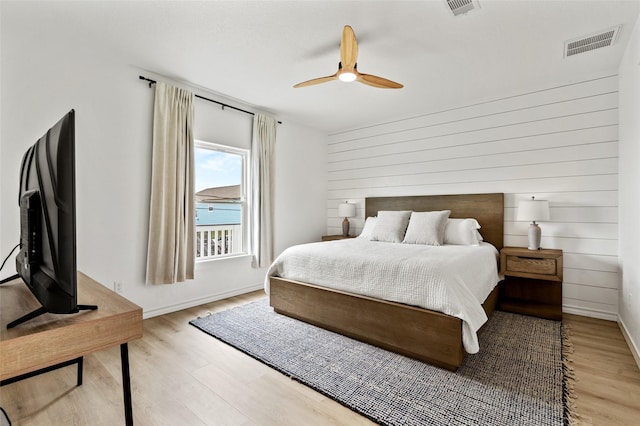 4214 Jackson Dr, Galveston, TX 77554 - bedroom with light wood-style floors, ceiling fan, wooden walls, and visible vents