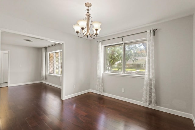 unfurnished room with a chandelier, baseboards, and wood finished floors