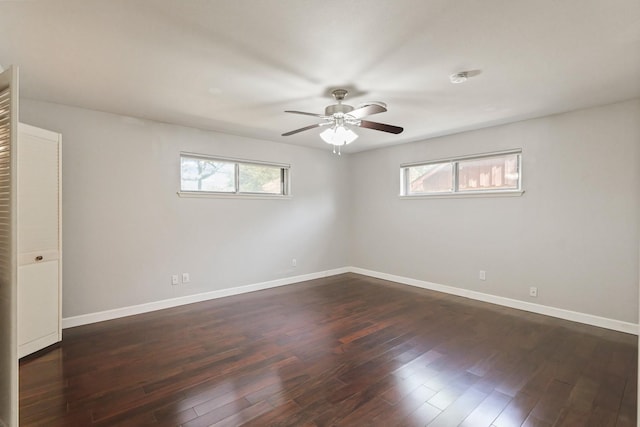 spare room featuring a healthy amount of sunlight, ceiling fan, baseboards, and dark wood-style flooring