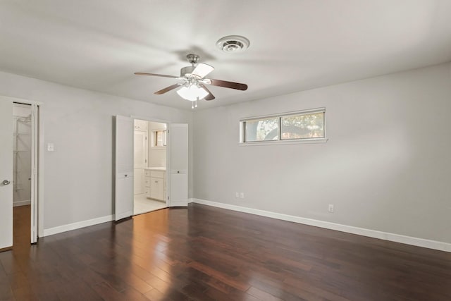 unfurnished bedroom featuring baseboards, visible vents, connected bathroom, dark wood-style floors, and ceiling fan