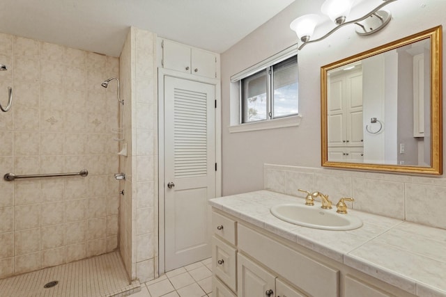 full bath with tasteful backsplash, a tile shower, vanity, and tile patterned floors