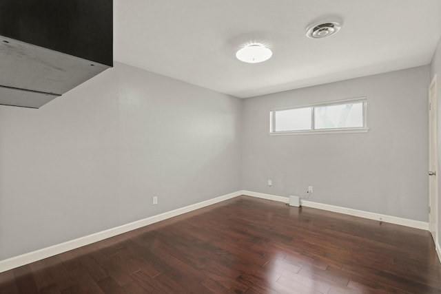 empty room featuring wood finished floors, visible vents, and baseboards