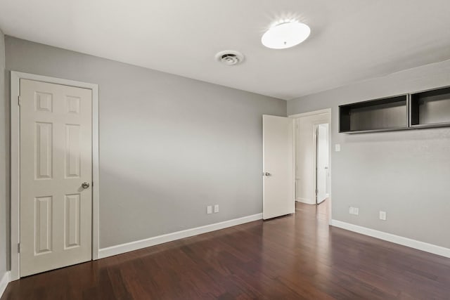 unfurnished bedroom with a closet, visible vents, baseboards, and wood finished floors