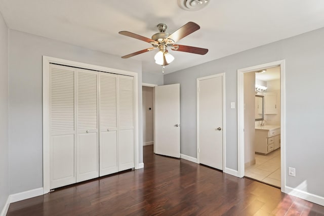 unfurnished bedroom featuring baseboards, a ceiling fan, connected bathroom, wood finished floors, and a closet