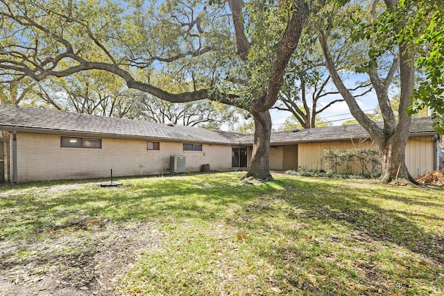 rear view of house featuring a yard, brick siding, and cooling unit