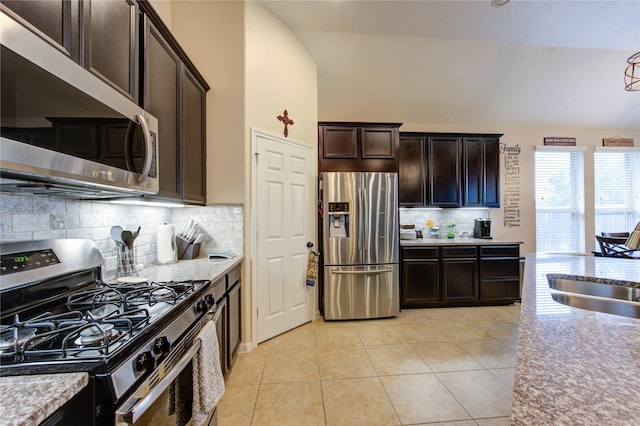 kitchen featuring light tile patterned floors, stainless steel appliances, a sink, dark brown cabinets, and backsplash