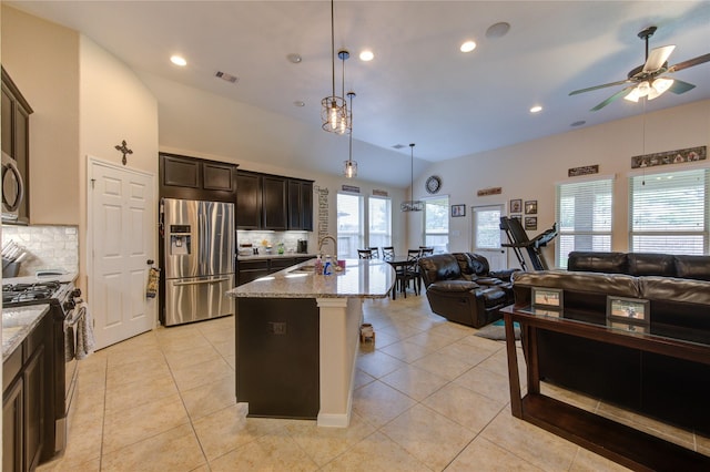 kitchen with appliances with stainless steel finishes, open floor plan, a sink, and light tile patterned floors