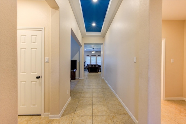 corridor with light tile patterned floors, ornamental molding, and baseboards