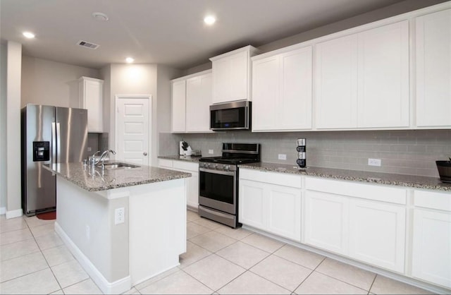 kitchen with light stone counters, a sink, visible vents, appliances with stainless steel finishes, and backsplash