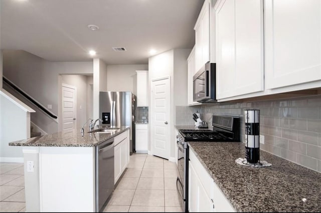 kitchen featuring light tile patterned floors, stainless steel appliances, tasteful backsplash, visible vents, and dark stone countertops