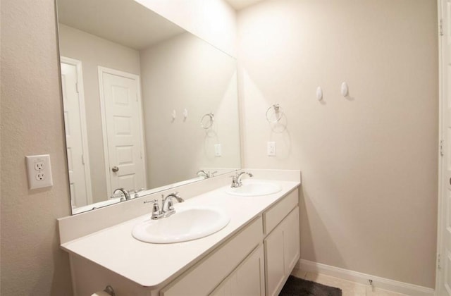 bathroom with tile patterned flooring, a sink, baseboards, and double vanity