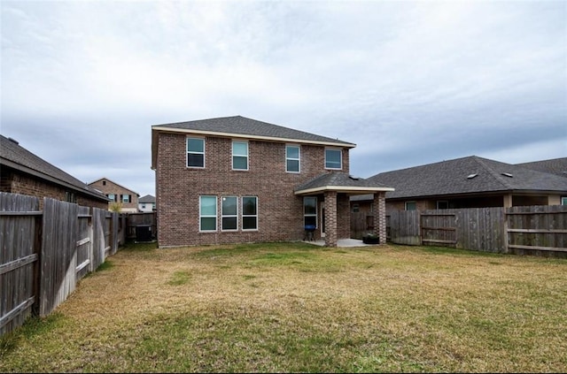 back of house featuring a yard, a fenced backyard, and brick siding