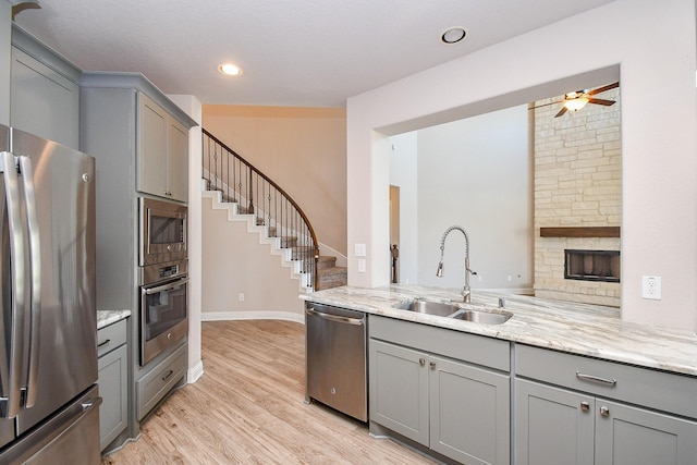 kitchen with gray cabinets, appliances with stainless steel finishes, ceiling fan, and a sink