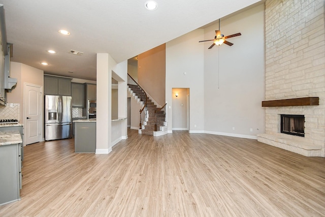 unfurnished living room featuring a fireplace, visible vents, a ceiling fan, and light wood-type flooring