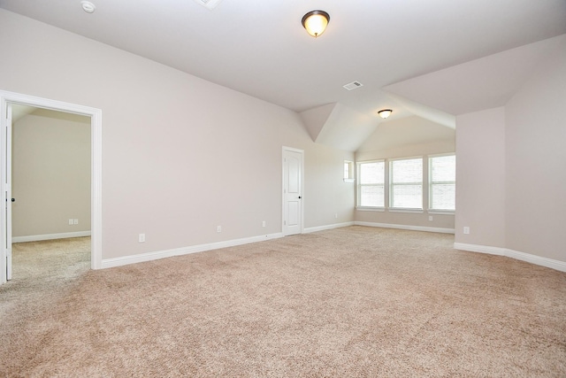 empty room with light carpet, visible vents, baseboards, and vaulted ceiling