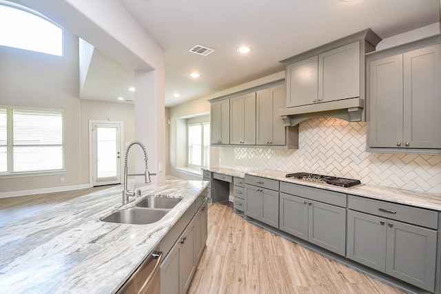 kitchen with under cabinet range hood, visible vents, gray cabinets, and a sink