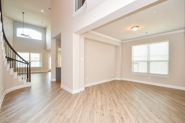 empty room featuring light wood-style flooring, baseboards, stairs, and ceiling fan