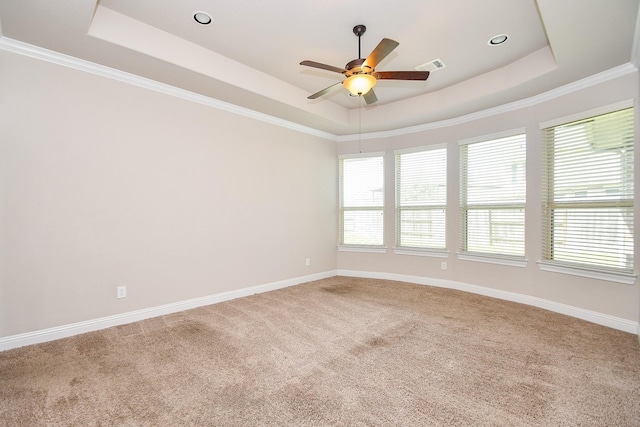 carpeted spare room with a raised ceiling, a ceiling fan, visible vents, and baseboards