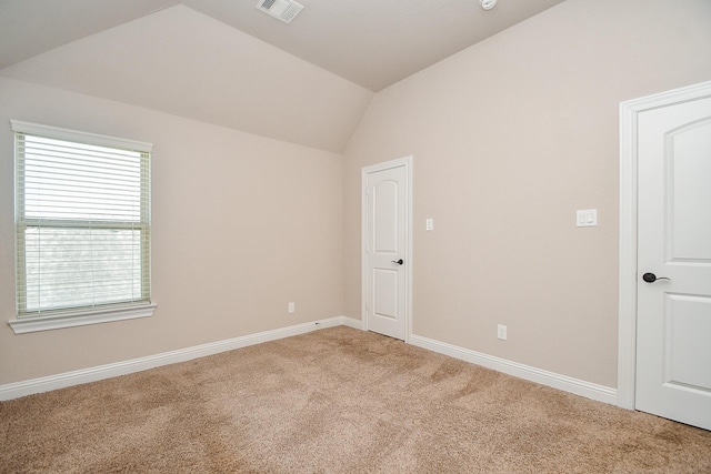 unfurnished room featuring vaulted ceiling, light colored carpet, visible vents, and baseboards