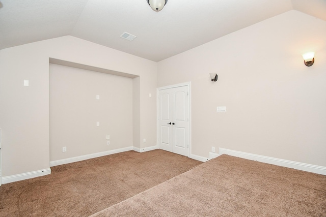 carpeted spare room featuring visible vents, baseboards, and vaulted ceiling