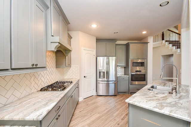 kitchen featuring a sink, gray cabinetry, light wood-type flooring, and stainless steel appliances