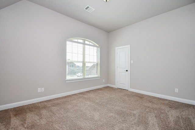 empty room with visible vents, light carpet, lofted ceiling, and baseboards