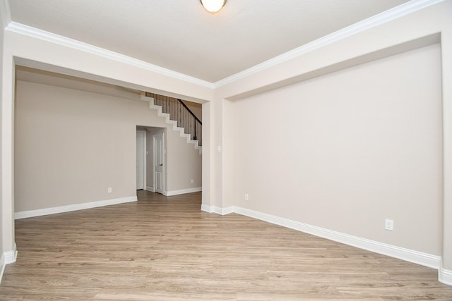 below grade area with stairs, light wood-type flooring, baseboards, and crown molding