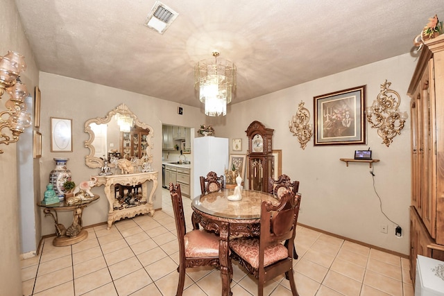 dining space with a notable chandelier, light tile patterned floors, visible vents, a textured ceiling, and baseboards