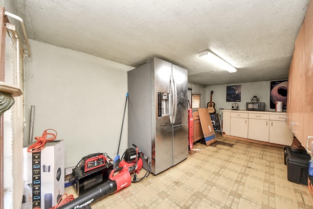 kitchen featuring light countertops, a textured ceiling, light floors, black microwave, and stainless steel refrigerator with ice dispenser