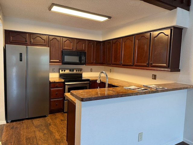 6341 Shadow Tree Dr, Houston, TX 77035 - kitchen featuring stainless steel appliances, a peninsula, dark brown cabinetry, dark wood-type flooring, and dark countertops