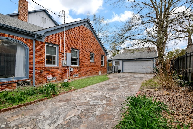 view of property exterior with fence, board and batten siding, an outdoor structure, brick siding, and a chimney