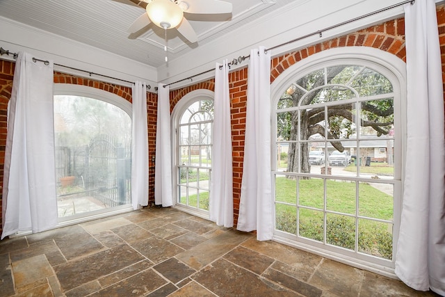 interior space featuring stone tile flooring, crown molding, and a ceiling fan