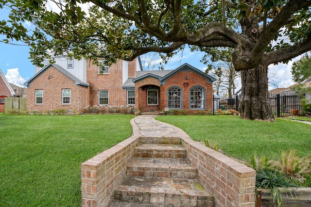 view of front of home featuring a front yard, fence, and brick siding