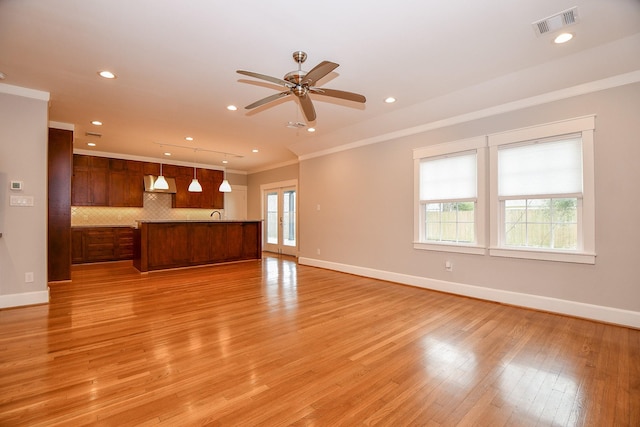 unfurnished living room with visible vents, baseboards, light wood-style floors, and ornamental molding