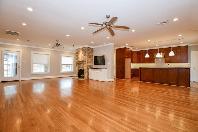 unfurnished living room featuring light wood-style floors, visible vents, and ornamental molding