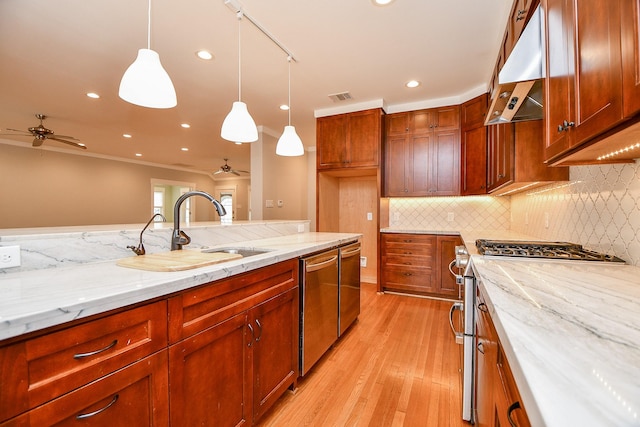 kitchen with visible vents, a sink, appliances with stainless steel finishes, pendant lighting, and exhaust hood