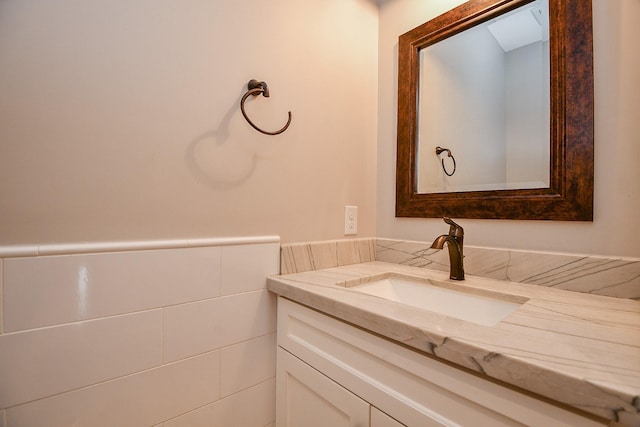 bathroom with a wainscoted wall, tile walls, and vanity