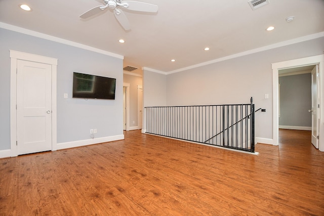 spare room featuring visible vents, baseboards, wood finished floors, and crown molding