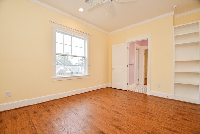 unfurnished room featuring built in features, wood finished floors, baseboards, and ornamental molding