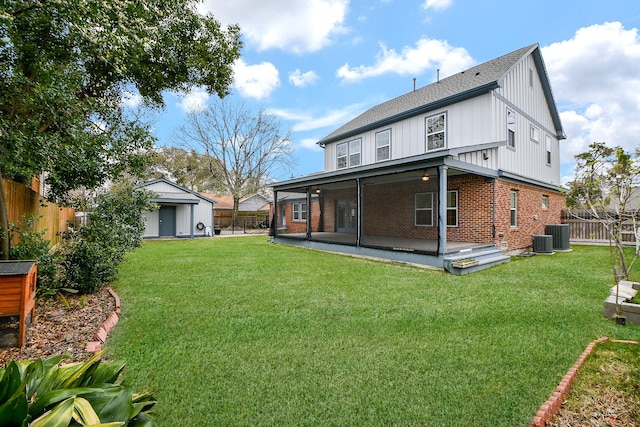 rear view of property featuring brick siding, a lawn, an outbuilding, and a fenced backyard