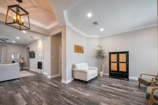 living area featuring dark wood-style floors, arched walkways, a fireplace, visible vents, and baseboards