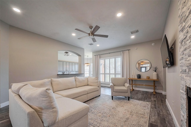 living area featuring visible vents, dark wood finished floors, baseboards, ceiling fan, and a fireplace