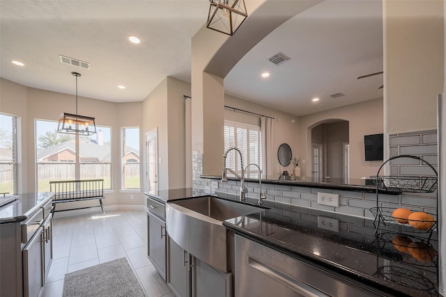 kitchen with tasteful backsplash, arched walkways, visible vents, and a sink